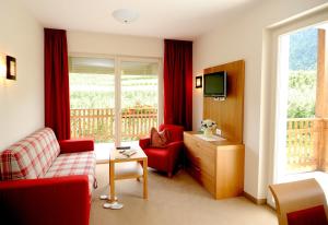 a living room with red furniture and a balcony at Feldhof Schenna in Schenna