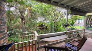 a porch with a bench and some trees at Nature's Melody Share Home in Brisbane