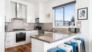 a kitchen with white cabinets and a large window at Anchorage in Apollo Bay