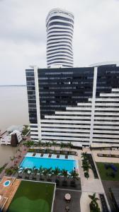a large building with a swimming pool in front of it at Puerto Santa Ana Luxury Suites Guayaquil in Guayaquil