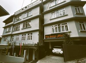 um edifício branco com um sinal em frente em The Better Inn em Gangtok