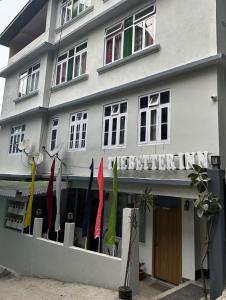 um edifício branco com guarda-chuvas coloridos à sua frente em The Better Inn em Gangtok