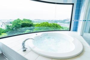 un bagno con vasca e ampia finestra di Hotel Sanderson a Maebashi