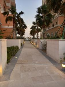 a walkway between two buildings with palm trees at Luxury Sea View Apartment with Amazing Amenities at Pearl Qatar in Doha
