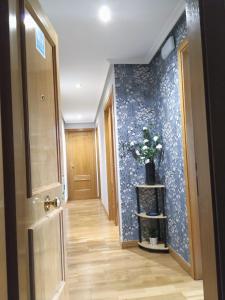 a hallway with a blue wall with a vase of flowers at Apartamento en OVIEDO,WIFI in Oviedo