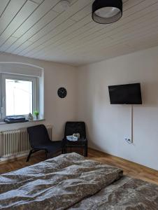 ein Schlafzimmer mit einem Bett, einem Stuhl und einem TV in der Unterkunft Pensionszimmer Larifari in Drees