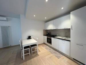 a kitchen with white cabinets and a table with chairs at Appartato a 5 minuti dal mare in Imperia