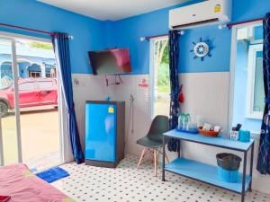een slaapkamer met een blauwe muur, een bureau en een televisie bij Sichon Lalla Beach สิชล ลัลลา บีช in Sichon