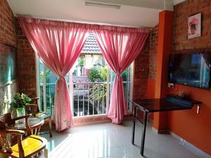 Habitación con una ventana con cortinas rosas y escritorio. en Homestay Syams, en Kampong Kubang Bemban