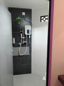 y baño con ducha y luz verde. en Homestay Syams, en Kampong Kubang Bemban