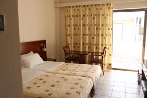 Schlafzimmer mit einem Bett, einem Tisch und einem Fenster in der Unterkunft LEPANTO BEACH HOTEL in Nafpaktos