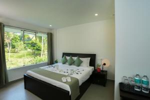 a bedroom with a large bed with a large window at SATRA WAYANAD in Kalpetta