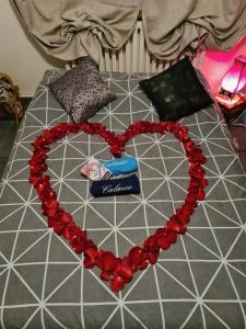 Un cuore fatto di perline rosse su un letto di Chambre avec Spa et Sauna privatisés a Bourg-en-Bresse