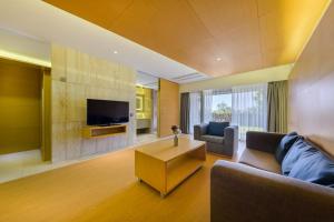 a living room with a couch and a tv at STANFORD Hotel & Resort Jeju in Jeju