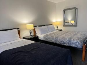 a hotel room with two beds and a mirror at Cooks Endeavour Motor Inn in Tweed Heads