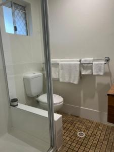 a bathroom with a toilet and a shower with towels at Cooks Endeavour Motor Inn in Tweed Heads
