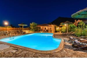una piscina notturna con sedie e ombrelloni di Villa Kambia a Plaka