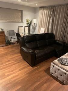 a living room with a black leather couch and a table at Luxurious Furnished Property in Stanmore