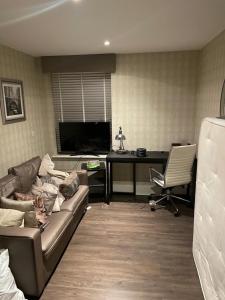 een woonkamer met een bank en een bureau bij Luxurious Furnished Property in Stanmore