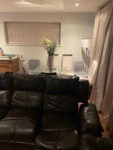 a living room with a black leather couch and a table at Luxurious Furnished Property in Stanmore