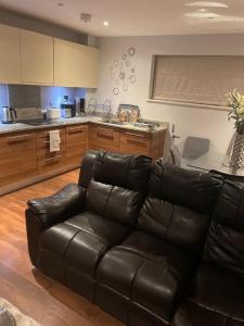 a living room with a leather couch and a kitchen at Luxurious Furnished Property in Stanmore