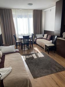 Cette chambre d'hôtel comprend deux lits, une table et des chaises. dans l'établissement Iglika 2 Ski Apartment, à Borovets