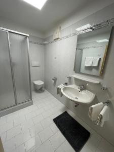 La salle de bains blanche est pourvue d'une douche et d'un lavabo. dans l'établissement Blummerhof, à Lagundo