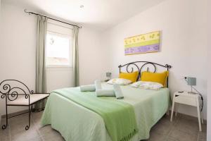 a bedroom with a large bed with a green blanket at C´AN PICAFORT NEAR THE SEA in Can Picafort