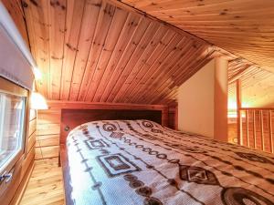 a bed in a room with a wooden ceiling at Peaceful log cabin in the country in Nurmijärvi