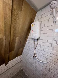 a shower in a bathroom with a white tile wall at ทุ่งดินดำ Farm Stay in Ban Kho Wang