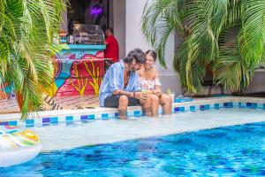 un hombre y una mujer sentados junto a una piscina en República Bahía Santa Marta Hostel, en Santa Marta