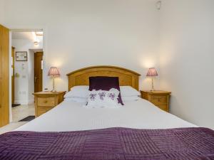 a bedroom with a large bed and two lamps at Appletree Cottage in Kirkton of Tealing