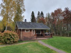een blokhut met een veranda in een tuin bij Peaceful log cabin in the country in Nurmijärvi