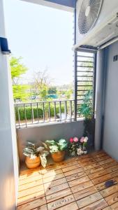 einen Balkon mit Topfpflanzen und einem großen Fenster in der Unterkunft Elio Del Ray in Bangkok