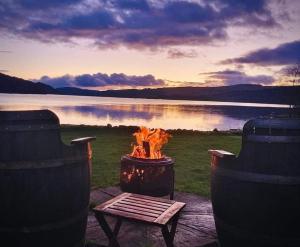 a fire pit with a bench next to a lake at Taychreggan Hotel in Kilchrenan
