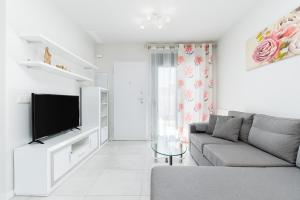 uma sala de estar branca com um sofá e uma televisão em Apartamento Milan em Campoamor