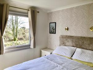 a bedroom with a bed and a window at Kilcoy Chalets in Muir of Ord