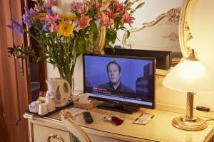 una televisione seduta su una scrivania con dei fiori di Hotel Commercio & Pellegrino a Venezia