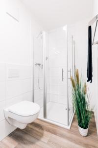 biała łazienka z toaletą i prysznicem w obiekcie Modernes Stadt-Apartement Mitte w mieście Bielefeld