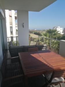 a balcony with a wooden table and a couch at Appt Bouznika EDEN ISLAND pied sur Mer in Bouznika