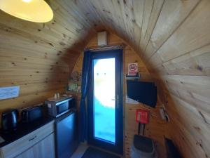 a small kitchen with a window in a wooden cabin at Hillside Camping Pods and Shepherd's Hut in Wick