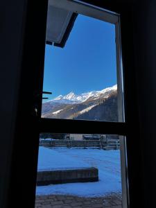 a view of a snowy mountain through a window at Bianchina - Bilocale con giardino privato in Valdisotto