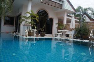 a swimming pool in front of a house at 4 Bedroom Superior South Pattaya Gated Villa Beachfront in Na Jomtien