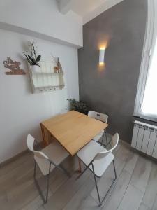 uma sala de jantar com uma mesa de madeira e cadeiras brancas em AMA AFFITTACAMERE em Albenga