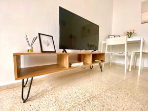 a living room with a television on a wooden table at Dúplex Centro Écija in Écija +22 photos