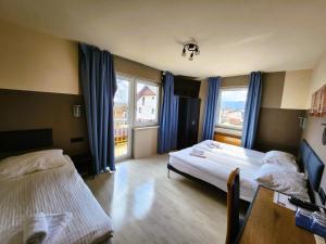 um quarto de hotel com duas camas e uma mesa e janelas em Pension Knafel em Žirovnica