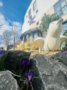 una statua di fronte a un edificio con fiori viola di Safranberg Hotel & Sauna a Ulma