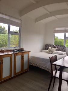 a bedroom with a bed and a table and two windows at Fynbos Tiny Home - Off Grid, Surrounded by Nature in Plettenberg Bay