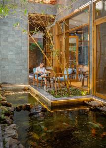 uma pessoa sentada numa cadeira ao lado de um lago em Daisy Boutique Hotel em Da Nang