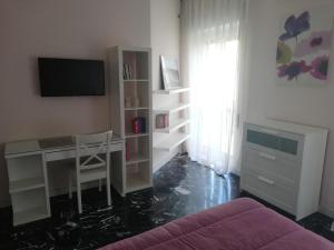 ein Wohnzimmer mit einem Schreibtisch und einem TV in der Unterkunft Casa Tevere in Syrakus